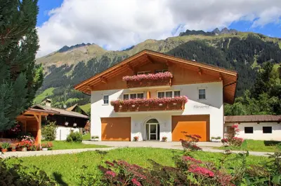 a house in the snow with mountains in the background at Wurzerhof Ratschings, ruhige Ferienwohnungen am Bauernhof mit Bergblick nahe Wander- & Skigebiet in Racines