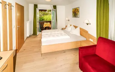 a bedroom with a bed and a red chair at Ferienwohungen Gamper in Tirolo
