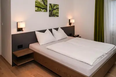 a bedroom with a large bed with white sheets and pillows at Ferienwohungen Gamper in Tirolo