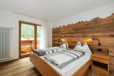 a bedroom with a bed with a wooden wall at Apartments San Vigilio in San Vigilio Di Marebbe