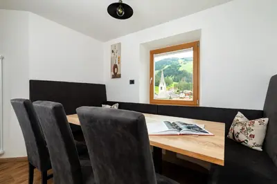a dining room table with chairs and a window at Apartments San Vigilio in San Vigilio Di Marebbe