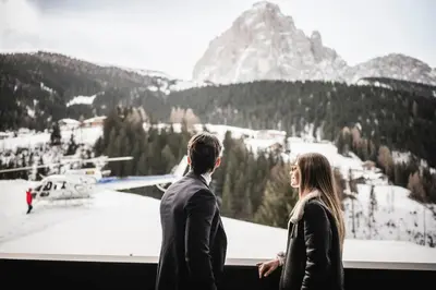 a man and woman standing in front of a view of a mountain at Luxury Chalet Alpurio in Selva di Val Gardena