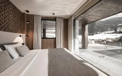 a bedroom with a large bed and a large window at Luxury Chalet Alpurio in Selva di Val Gardena