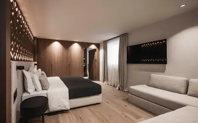 a bedroom with a bed and a couch at Luxury Chalet Alpurio in Selva di Val Gardena