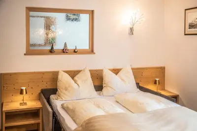 a bedroom with a bed with white sheets and pillows at La Odles in Selva di Val Gardena
