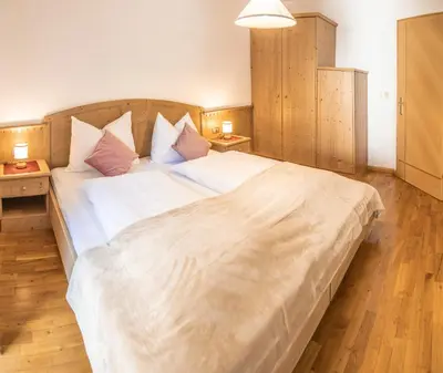 a bedroom with a large bed with white sheets and pink pillows at La Odles in Selva di Val Gardena