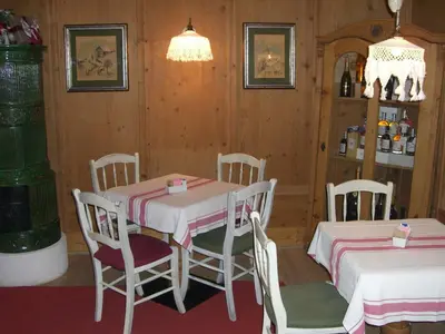 a dining room with two tables and chairs and a shelf at Ciasa Mancin Suite-Apartments in Moena