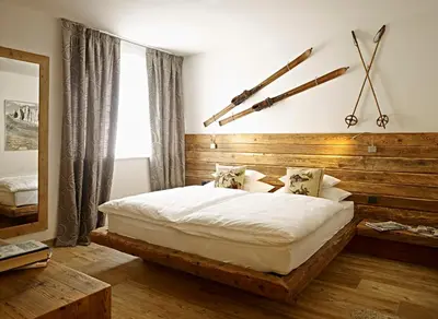 a bedroom with a bed with a wooden headboard at Ciasa Mancin Suite-Apartments in Moena