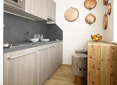 a kitchen with wooden cabinets and a bowl of fruit on a counter at Ciasa Mancin Suite-Apartments in Moena