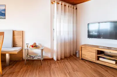 a living room with a television and a table with a chair at Ferienwohnungen Schweitzer in Parcines