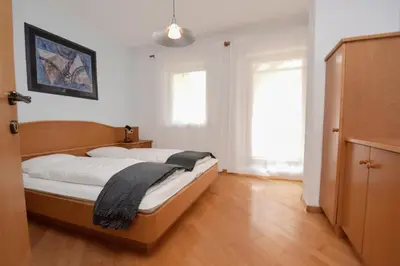 a bedroom with a bed with white sheets and a wooden floor at Aurturist Monguelfo Roulette in Monguelfo