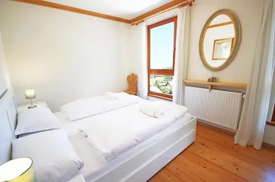 a white bedroom with a bed and a window at Aurturist Monguelfo Roulette in Monguelfo