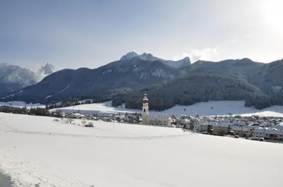 a town in the mountains with a snow covered field at Aurturist Villabassa in Villabassa