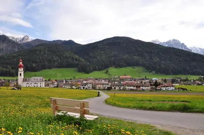 a bench sitting in a field next to a road at Aurturist Villabassa in Villabassa