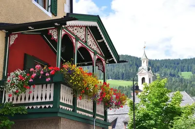 a balcony with flowers on a building with a church at Aurturist Villabassa in Villabassa