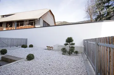 a backyard with a white wall and a fence at Aurturist Villabassa in Villabassa
