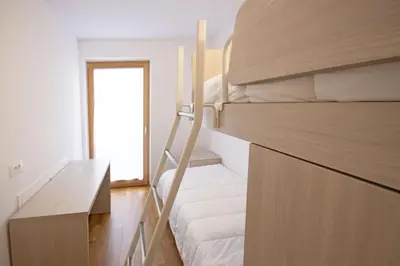 a bedroom with two bunk beds and a desk at Aurturist Villabassa in Villabassa