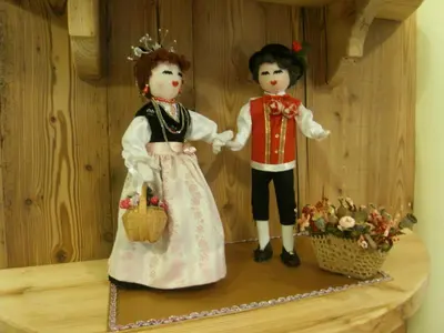 two dolls are standing on a wooden shelf at Hotel L'Ideale in Moena
