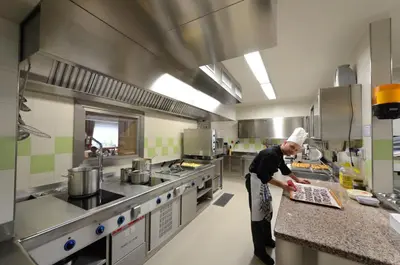 a chef preparing food in a large kitchen at Hotel L'Ideale in Moena