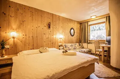 a bedroom with wooden walls and a bed and a couch at Cesa Sara in Ortisei