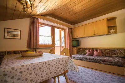 a room with a table and a bed and a window at Cesa Sara in Ortisei