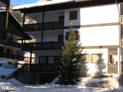 a christmas tree in the snow in front of a building at APPARTAMENTO VALENTINI in Campitello di Fassa