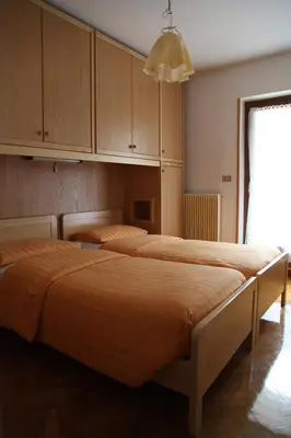 two beds in a room with cabinets and a window at APPARTAMENTO VALENTINI in Campitello di Fassa