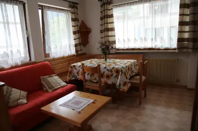 a living room with a table and a red couch at APPARTAMENTO VALENTINI in Campitello di Fassa