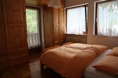 a bedroom with a bed and two windows at APPARTAMENTO VALENTINI in Campitello di Fassa