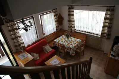 a living room with a table and a red couch at APPARTAMENTO VALENTINI in Campitello di Fassa