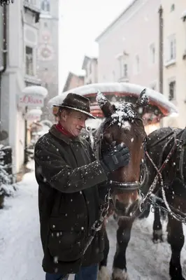 a man standing next to a horse in the snow at Ferienwohnungen Unterangerhof in Quinzo