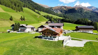 a village in a green field with houses and mountains at Ferienwohnungen Unterangerhof in Quinzo