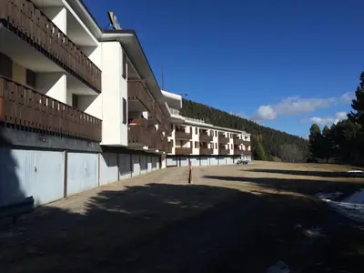 a large building with a parking lot in front of it at Appartamento Alpe di Siusi in Alpe di Siusi
