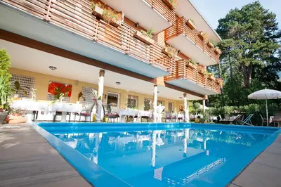 a pool at a hotel with tables and chairs at Hotel Aster in Merano