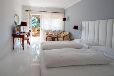 a bedroom with two beds and a table and chairs at Hotel Aster in Merano