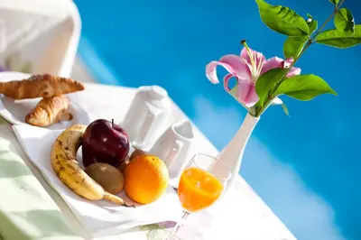 a tray of fruit and a vase with a flower at Hotel Aster in Merano