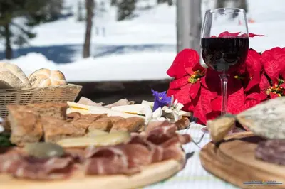 a table with a glass of wine and a plate of food at Miralago in Alleghe