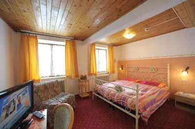a bedroom with a bed and a couch and a tv at Albergo Malga Ciapela in Rocca Pietore