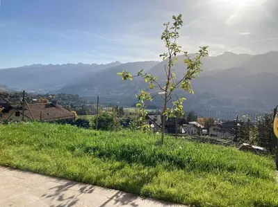 a field of green grass with houses and a fence at CASA DIAF appartamento incantevole Carano Ville di Fiemme in Carano