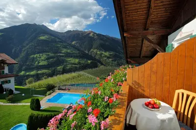 a table with a bowl of fruit and flowers on a balcony at Haus Bernhard in Schenna