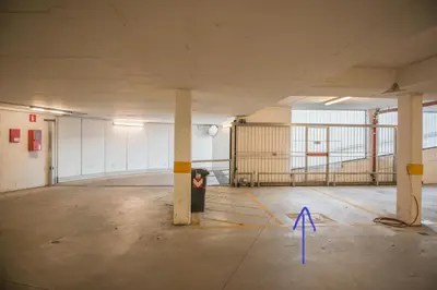 an empty parking garage with a blue arrow on the floor at Apartment mit Tiefgarage 8 Min zu Fuß bis ins Zentrum in Merano