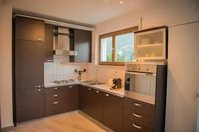 a large kitchen with brown cabinets and a window at Apartment mit Tiefgarage 8 Min zu Fuß bis ins Zentrum in Merano