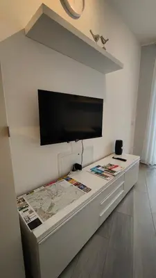 a room with a tv on a wall with a table at Apartment mit Tiefgarage 8 Min zu Fuß bis ins Zentrum in Merano