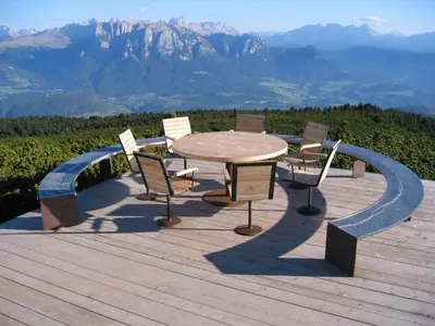 a table and chairs on a deck with a view of mountains at Hotel Regina in Soprabolzano