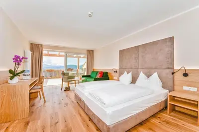 a hotel room with a large bed and a desk at Hotel Regina in Soprabolzano