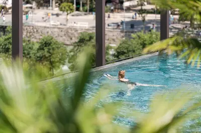 a woman is swimming in a swimming pool at Hotel Therme Meran - Terme Merano in Merano