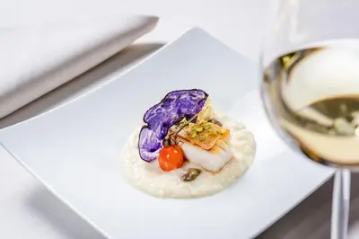 a plate of food next to a glass of wine at Hotel Therme Meran - Terme Merano in Merano