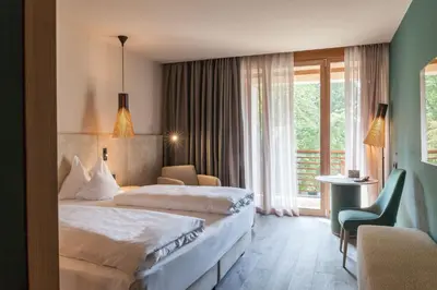 a hotel room with two beds and a balcony at Hotel Therme Meran - Terme Merano in Merano
