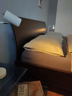 a bedroom with a bed with a lamp and a glass table at La Vista - Apartment mit Traumblick & Garten in Marlengo
