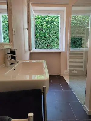 a bathroom with a sink and a large window at La Vista - Apartment mit Traumblick & Garten in Marlengo